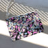 Rectangular wristlet clutch featuring a dark background with colorful bats, skulls, eyeballs, and vampire mouths. White strap and gold zipper visible.